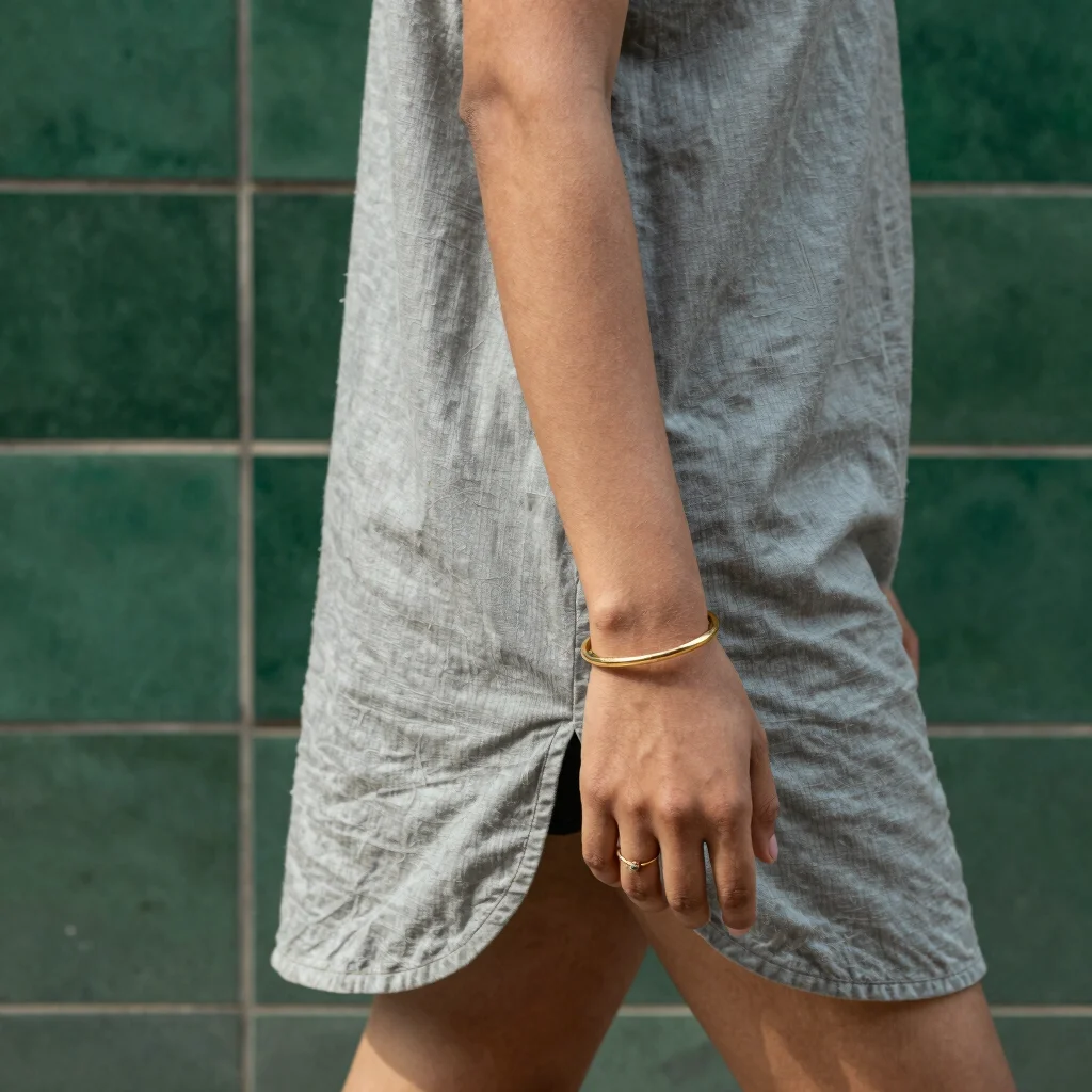 Woman in a casual shirt wearing a simple artificial bracelet while walking past a green-tiled wall in Karachi, natural d
